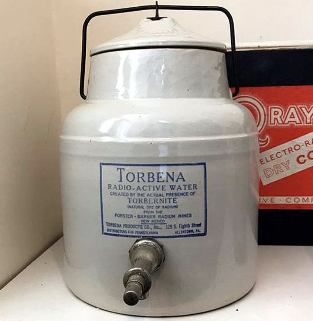 Vintage Torbena radioactive water pot with spigot, placed next to an old battery box
