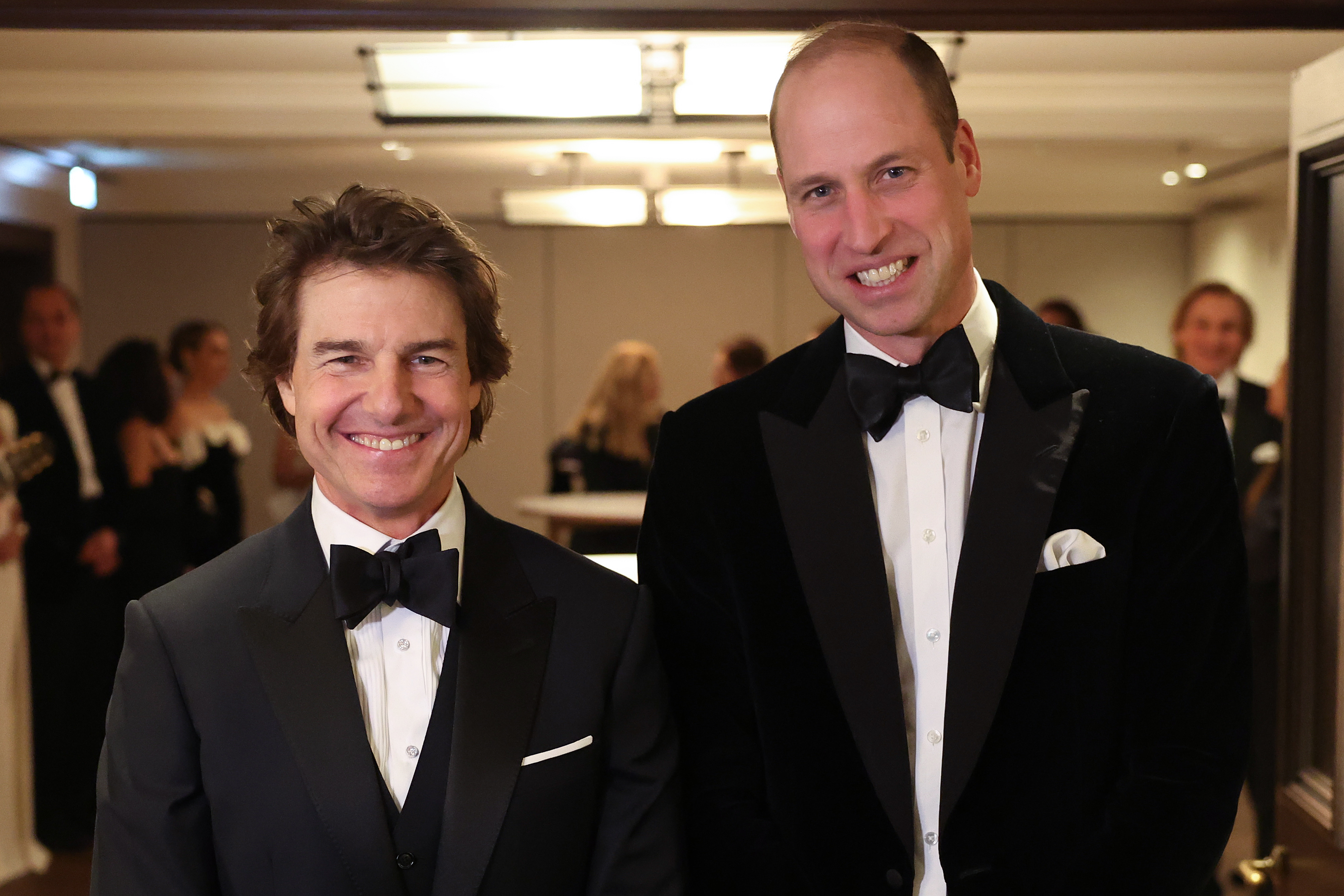 Two men in black-tie attire smiling at an event