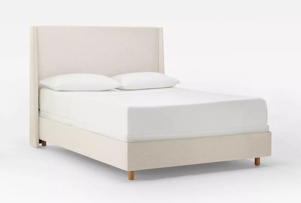 Modern upholstered bed with a minimalist design, featuring a headboard and wooden legs