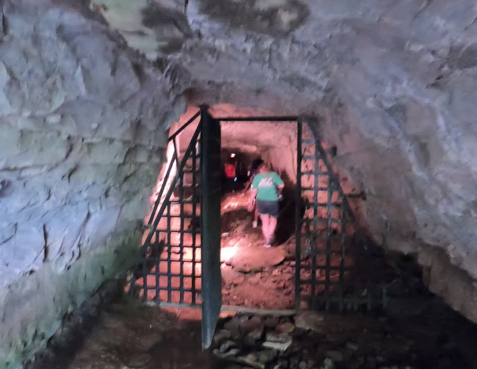 Person exploring a cave through a metal gate