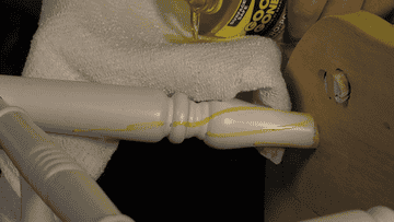 Close-up of a person&#x27;s hand applying Goo Gone to a wooden chair to remove dried up glue