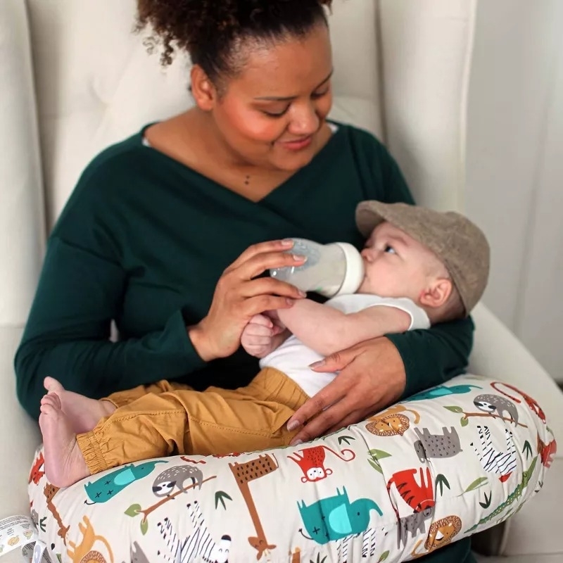model feeding baby with bottle, sitting with nursing pillow with animal print