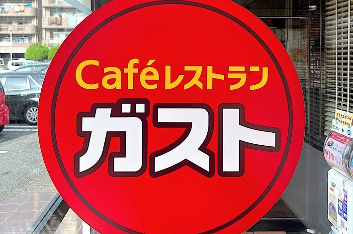 Sign for Café de Crie with red background and yellow text on a storefront window