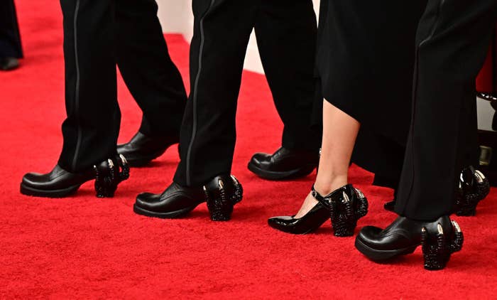 レッドカーペットでの人々の足元、ドレスとスーツのズボン、黒の靴を着用。
