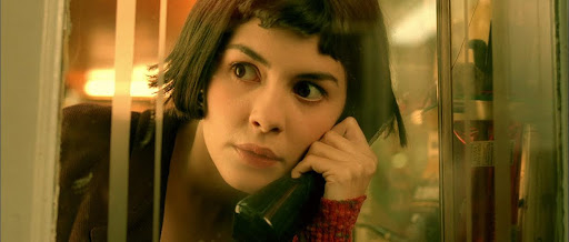 Woman with a bob haircut on a phone in a booth, looking pensive