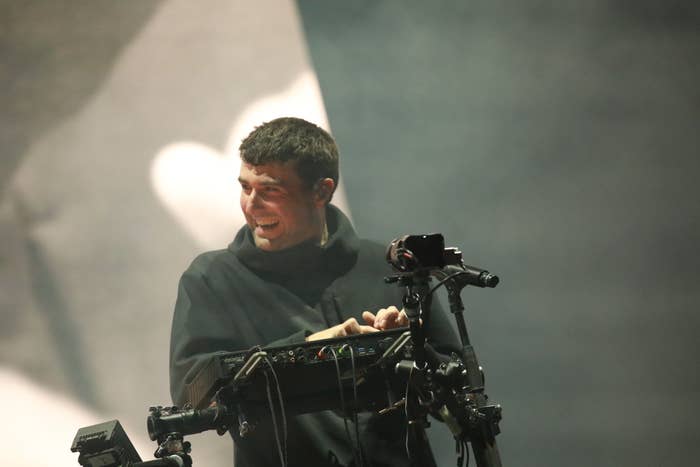 Man in a hoodie smiles while operating camera equipment on stage