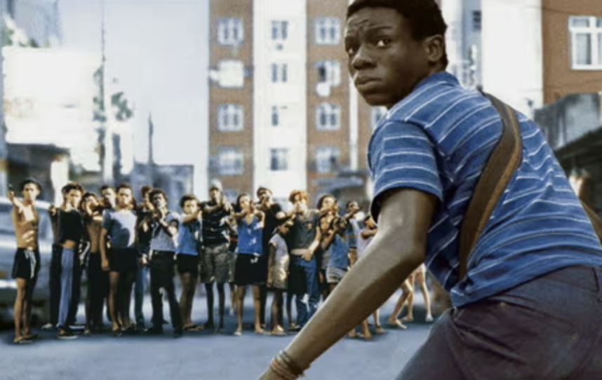 Man playing baseball with onlookers behind, scene from a film