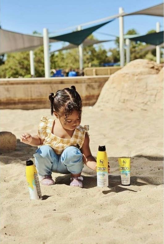 Child in playground with three sunscreen bottles, promoting outdoor sun protection