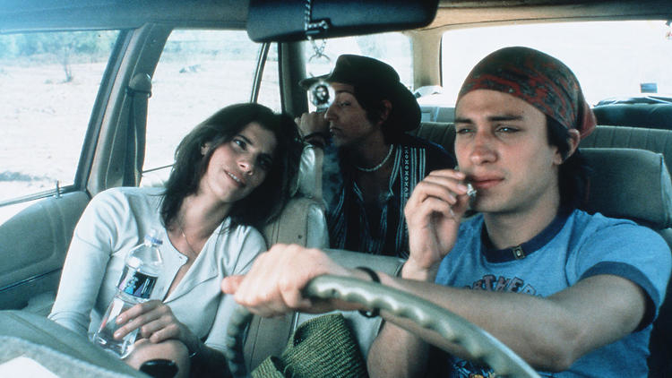 Three people in a vintage car; two men in the front; a woman in the backseat. The vibe is casual
