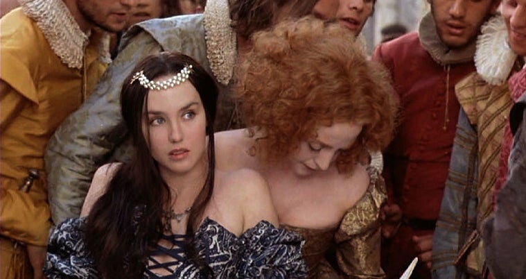 Two women in historical dresses, one with a tiara, in a crowd from the film 'Ever After'