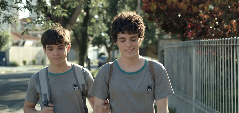 Two boys walking side by side, smiling, one with an arm over the other&#x27;s shoulder