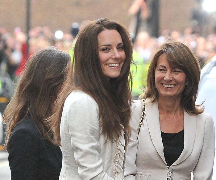 Kate Middleton in a white jacket smiling while next to her mother