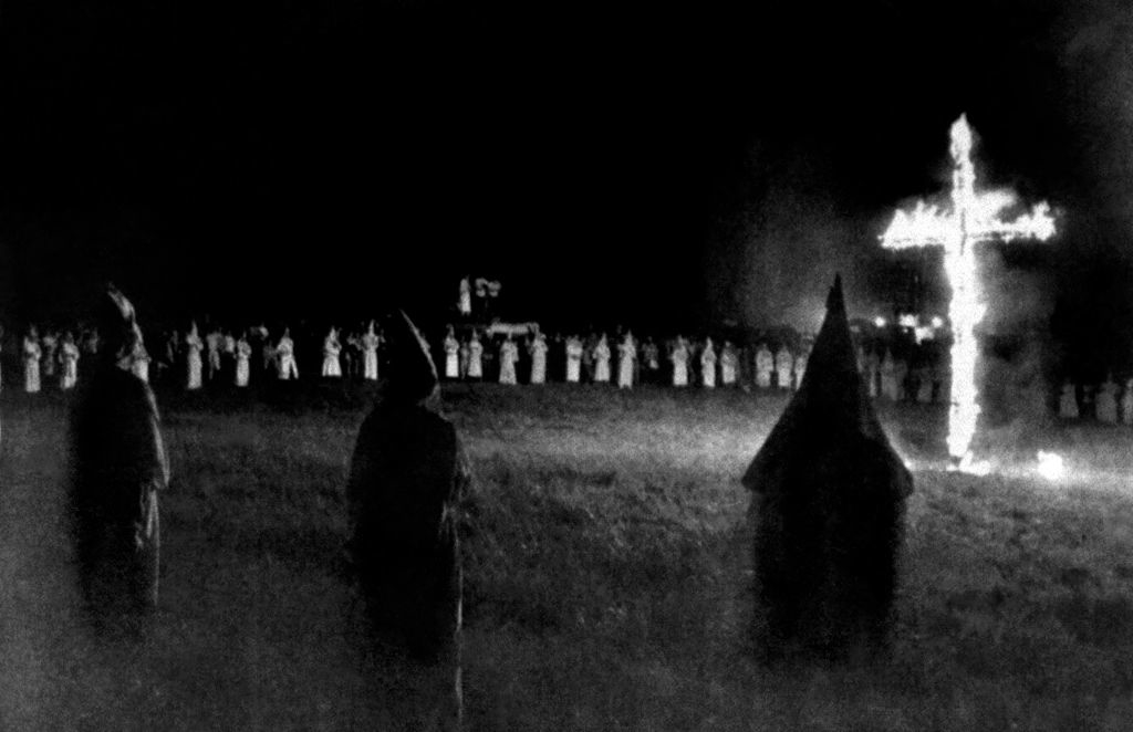 Image of a historical photograph depicting a cross burning with figures in robes