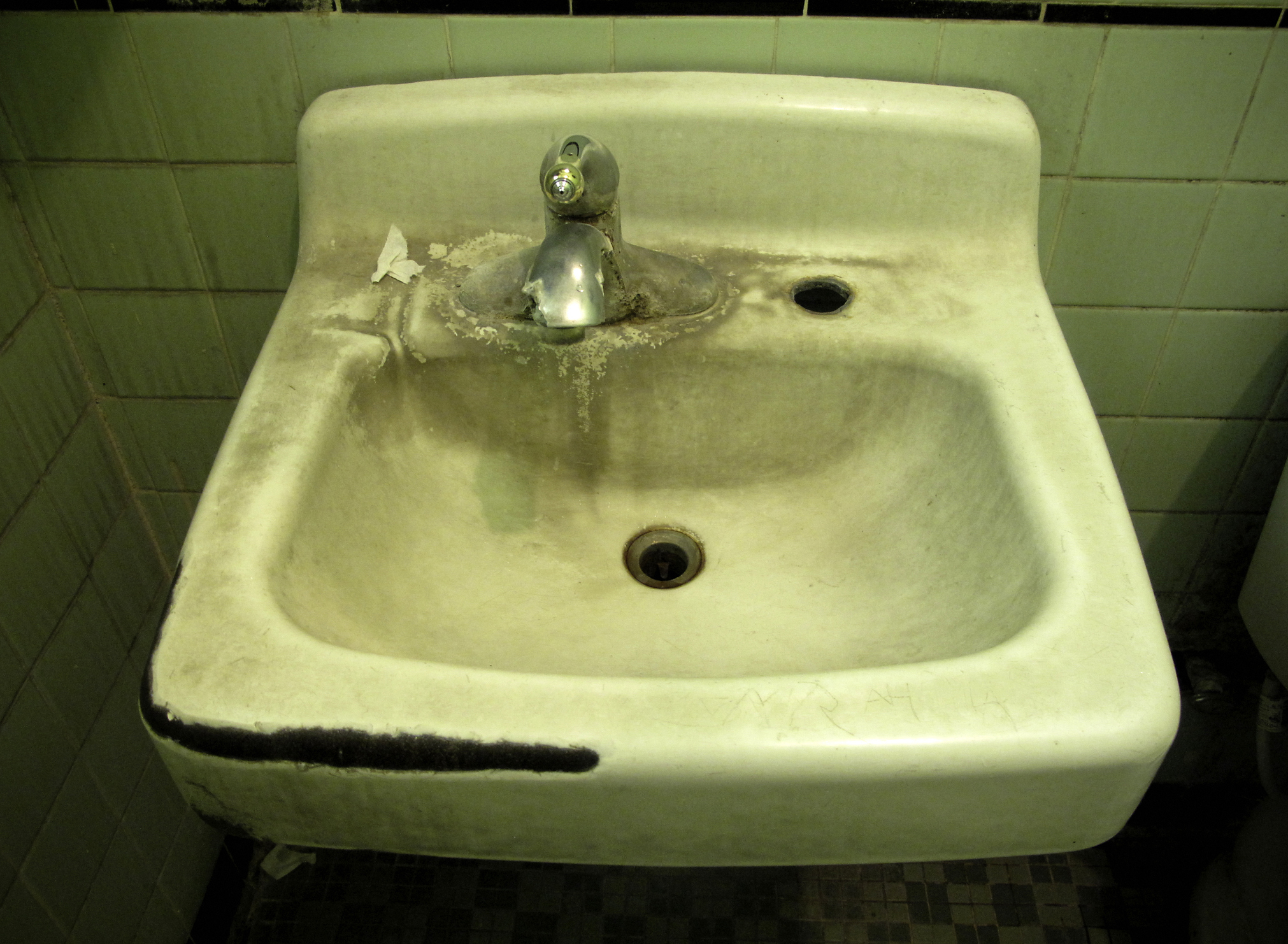 A neglected bathroom sink with visible stains and soap residue
