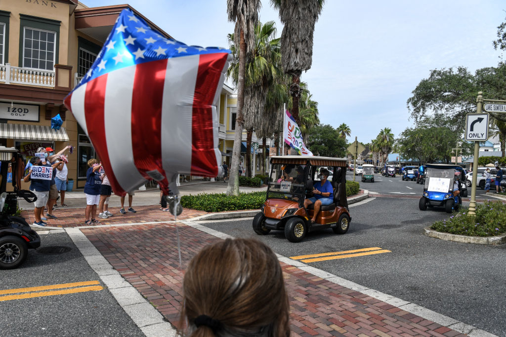 Star-shaped balloon with the American flag design, golf carts, and people at a street gathering