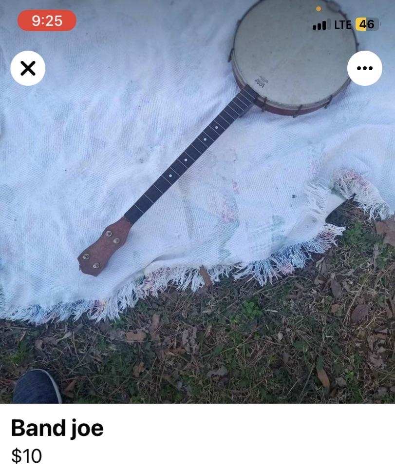 Banjo with damaged skin on a frayed blanket, grass background, screenshot of an online sale listing for a &quot;Band joe&quot; for $10