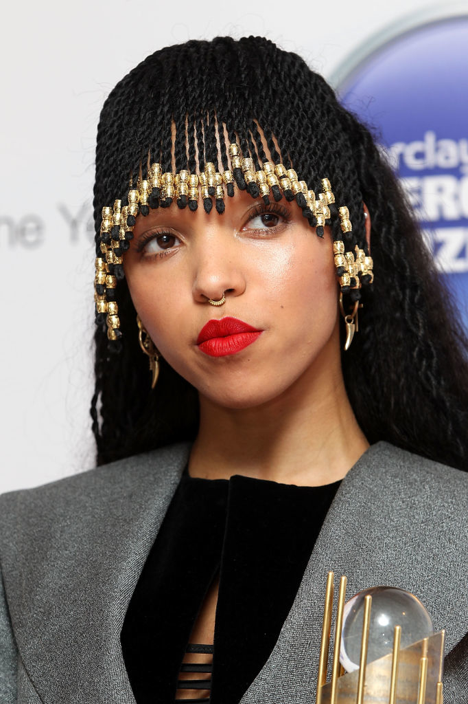 FKA with beaded braids holding an award, wearing a nose ring and a blazer