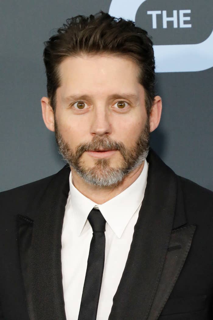 Brandon in a black suit and tie with styled hair and beard