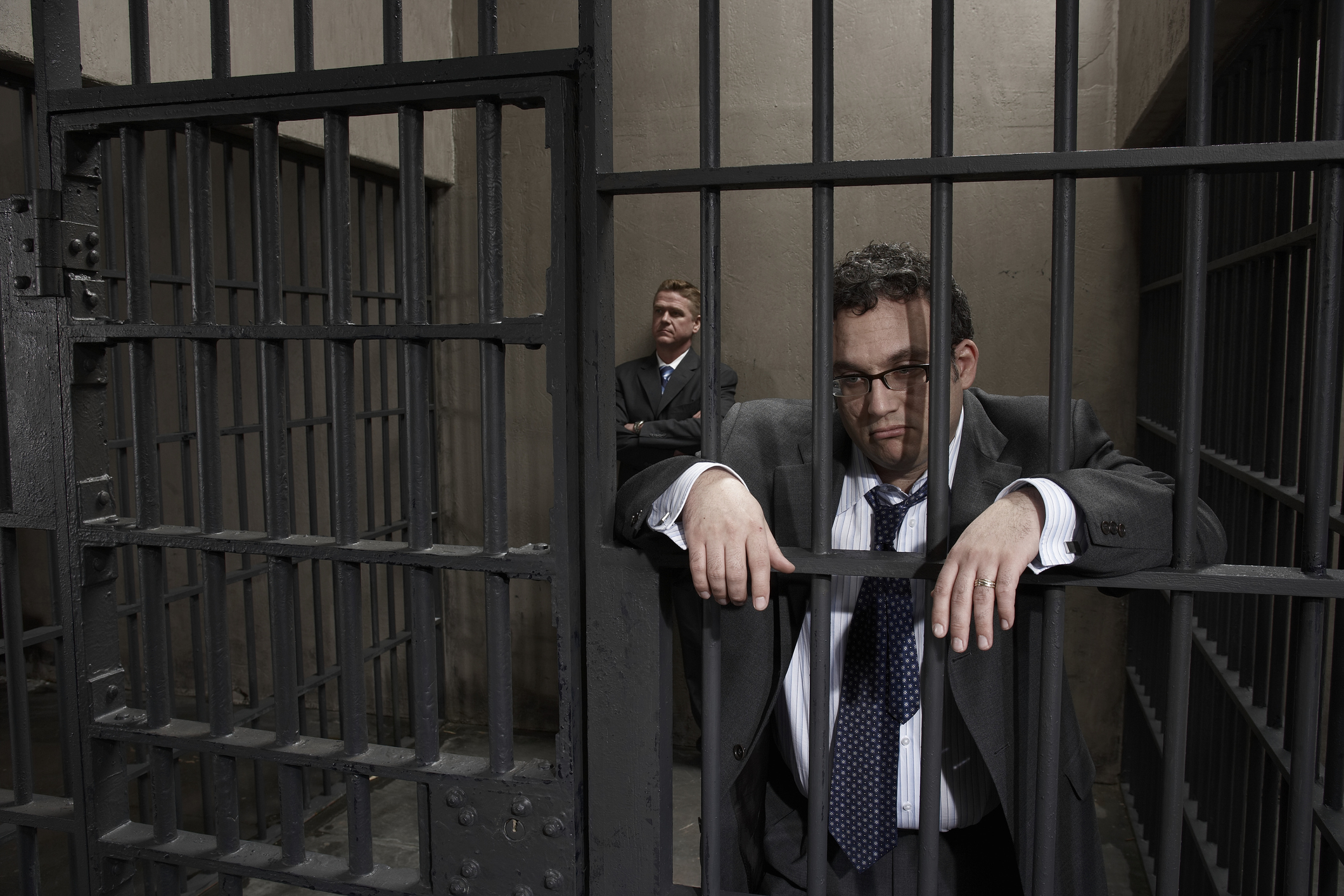 Two men in suits behind bars