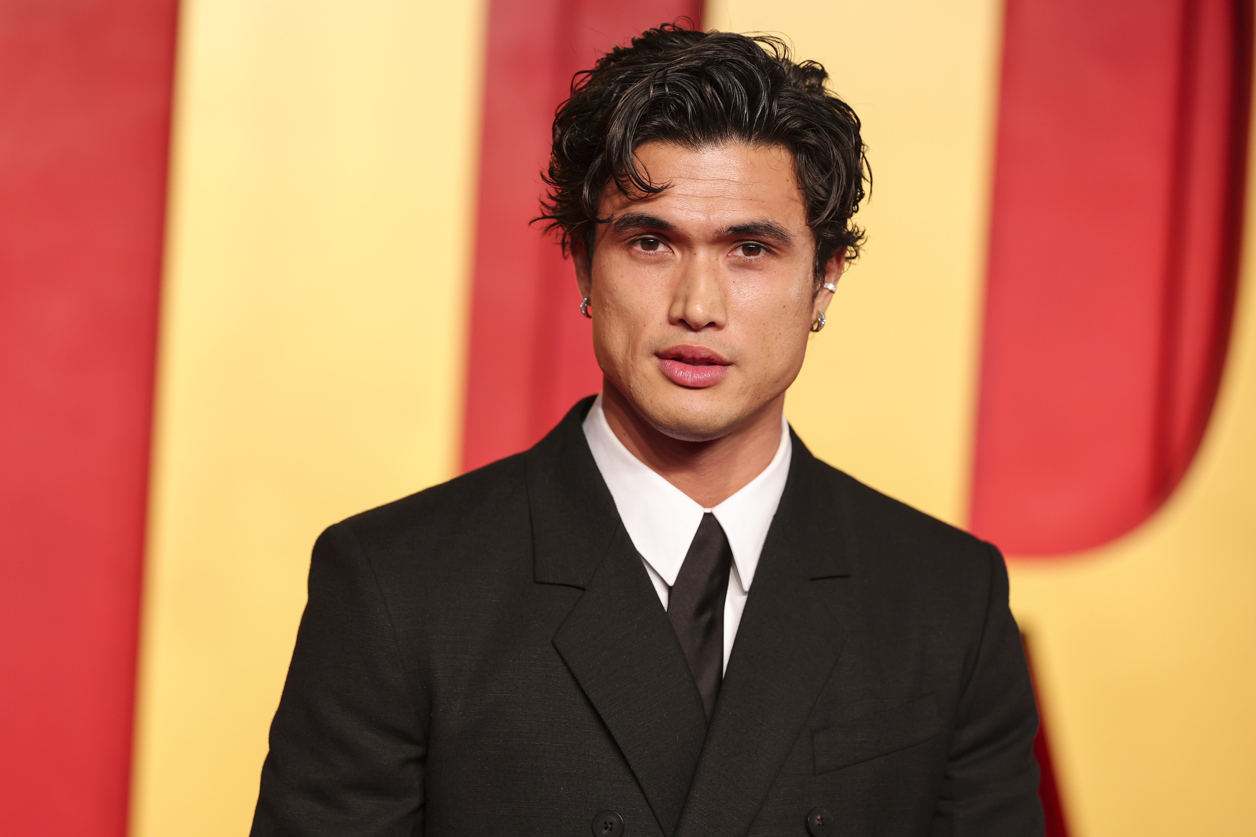 Charles Melton in a suit and tie at a media event