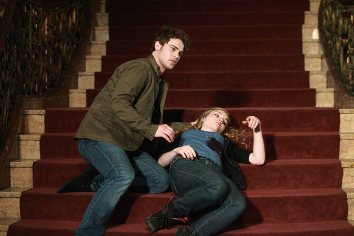 Brian and Chloe staged in a dramatic pose on a staircase, him standing bent over Chloe, who is lying back on the steps