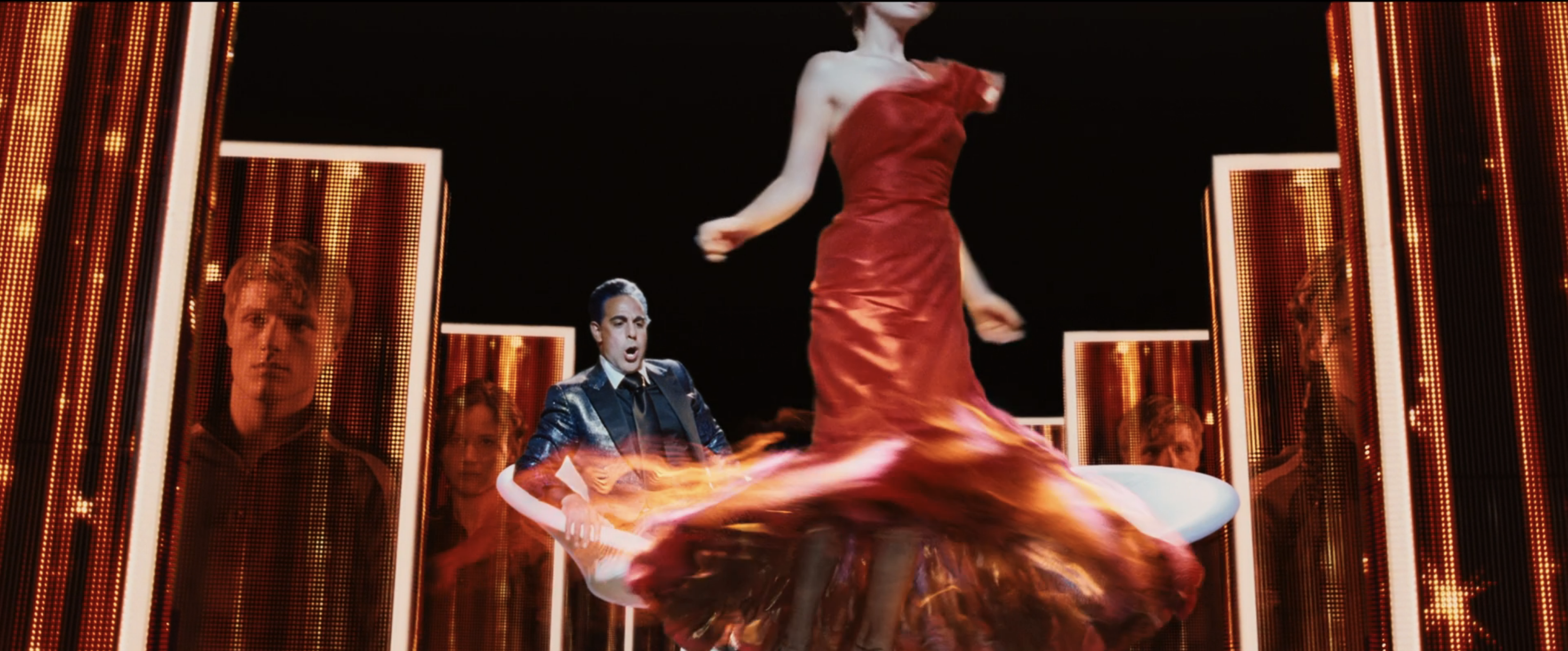 Katniss spins on her stage, the skirt of her dress catching fire