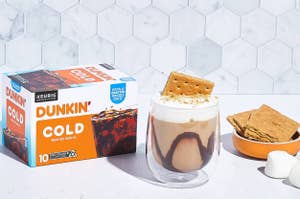 Dunkin' Cold Brew coffee box next to a glass of cold brew and snacks on a countertop