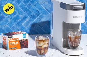 Keurig machine beside a Dunkin' Cold Brew box with a glass of iced coffee on a counter