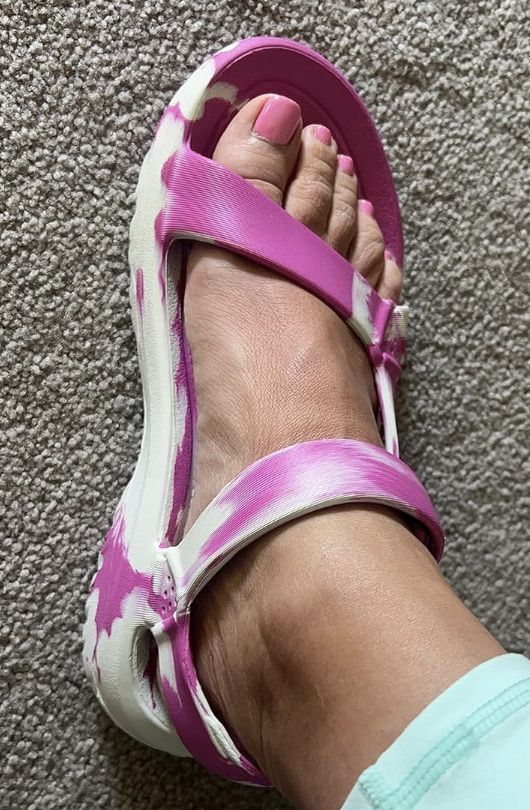 Foot wearing a white and pink patterned sandal