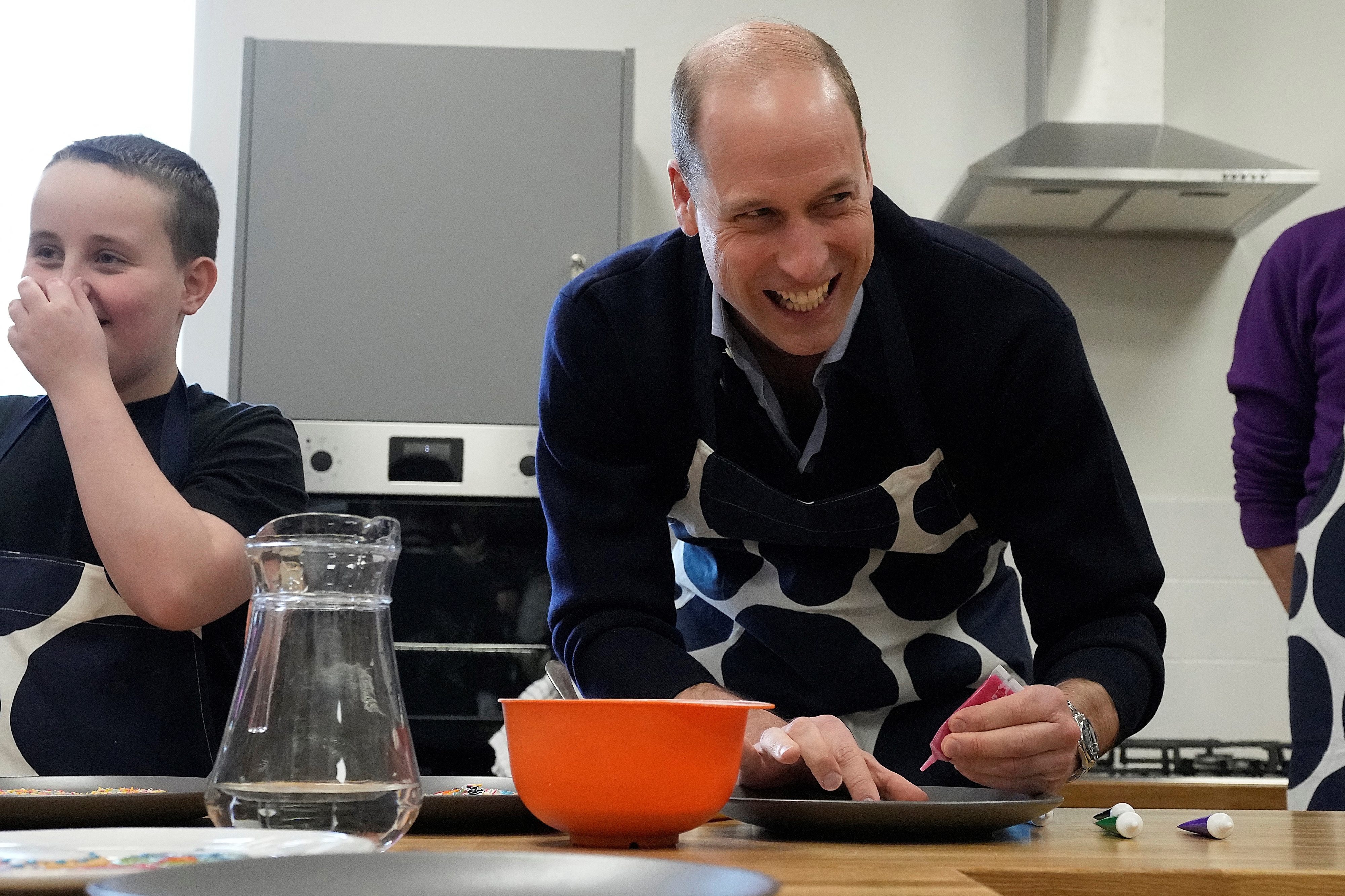 Prince William laughing with children during a cooking class
