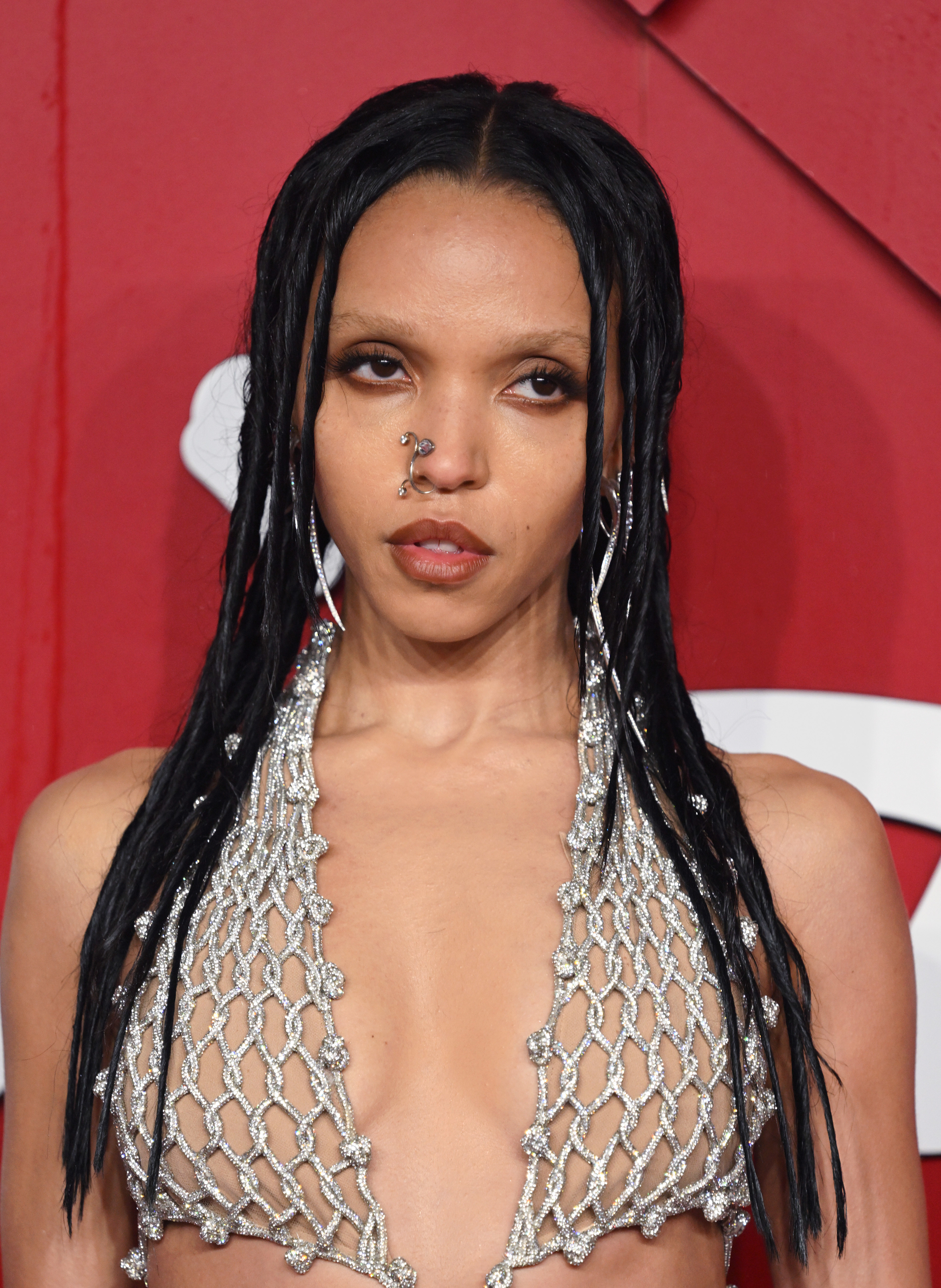Twigs with long dark hair, wearing a chainmail top, on a red carpet