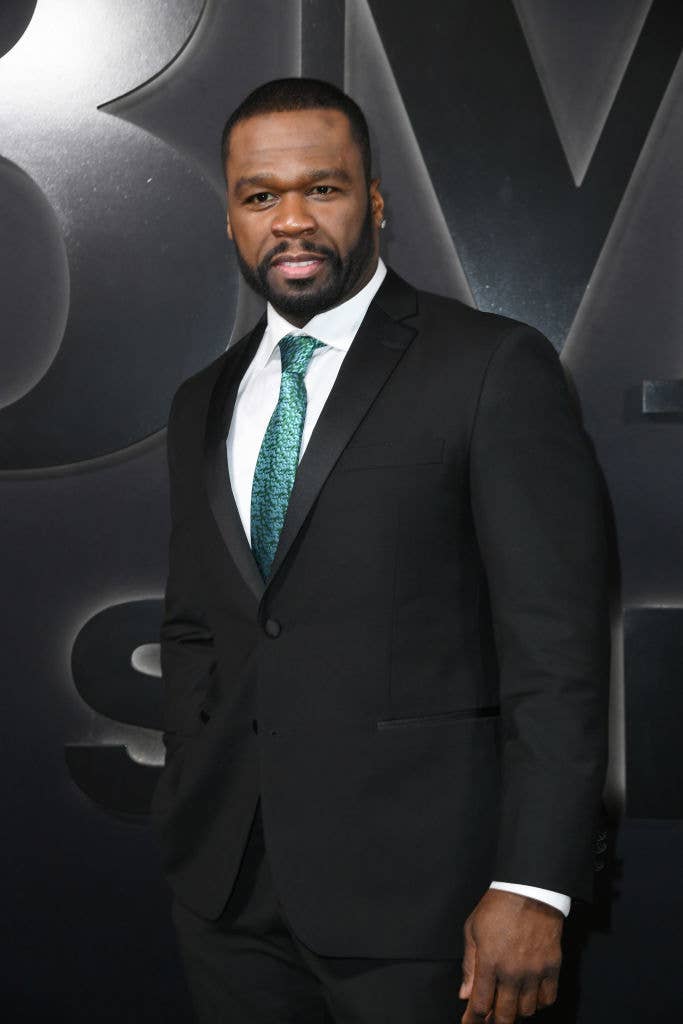Curtis "50 Cent" Jackson poses in a black suit with a green tie at an event