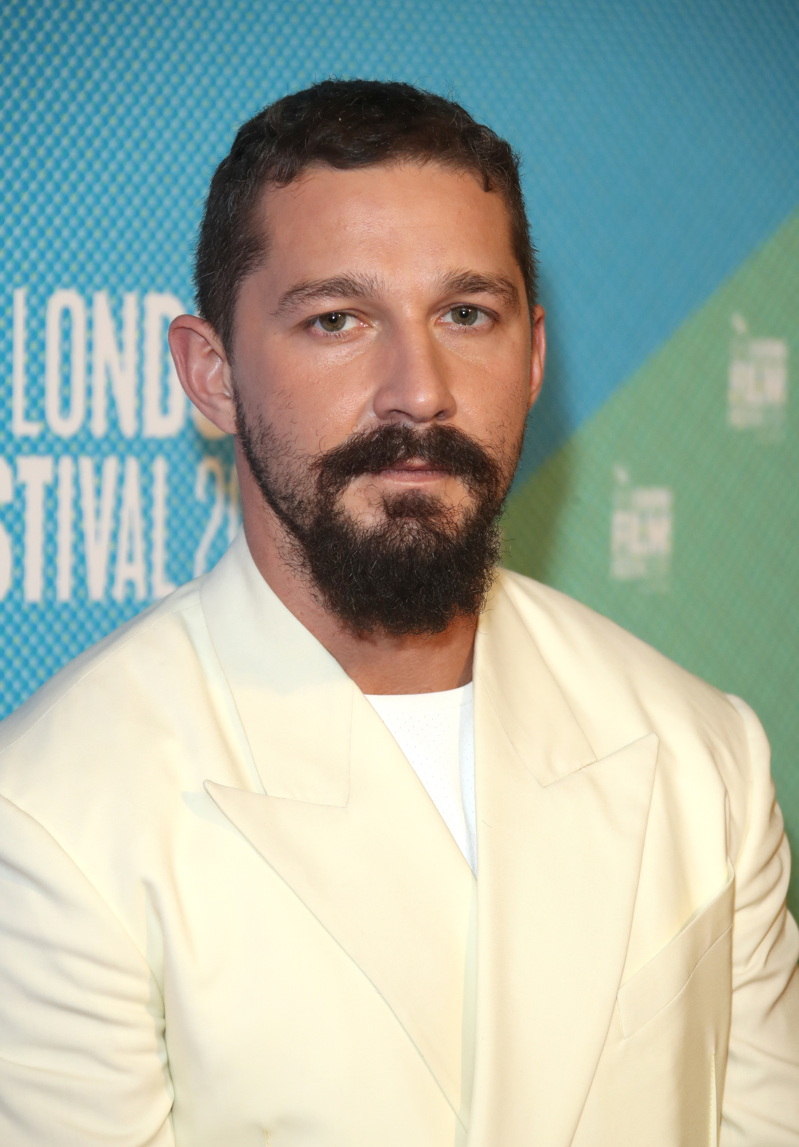 Shia with a beard in a light suit at an event