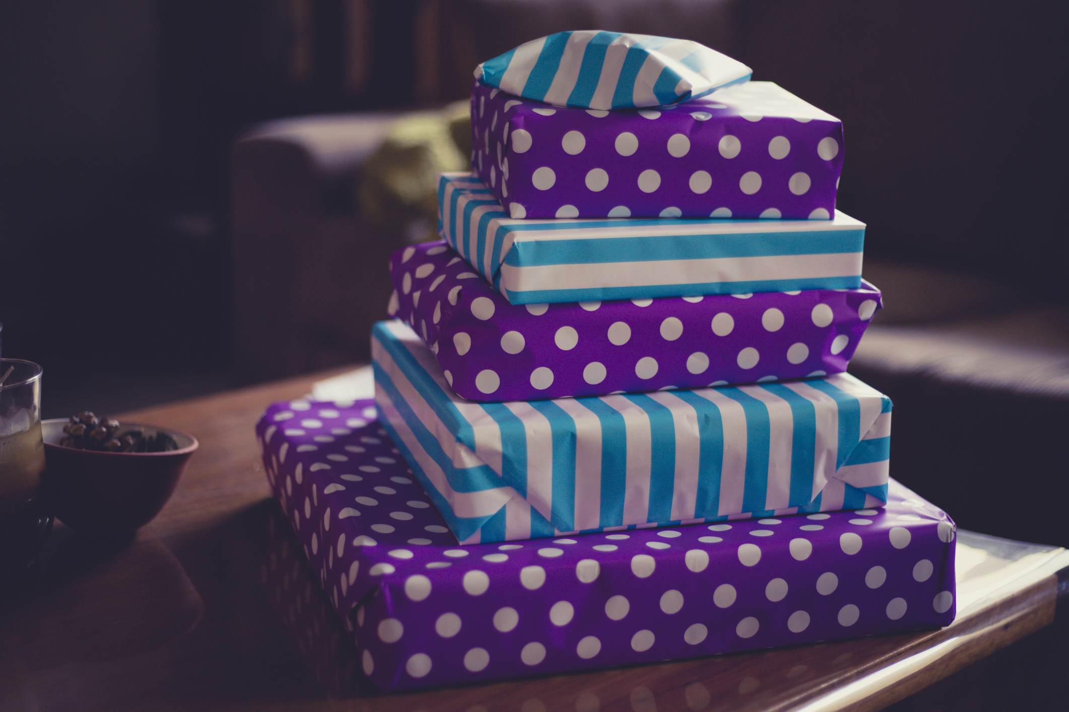 Three stacked gifts wrapped in blue and purple patterned paper