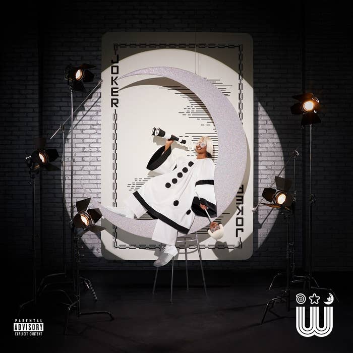 Album cover with artist in a futuristic white outfit posing inside a large letter &#x27;C&#x27; surrounded by studio lights