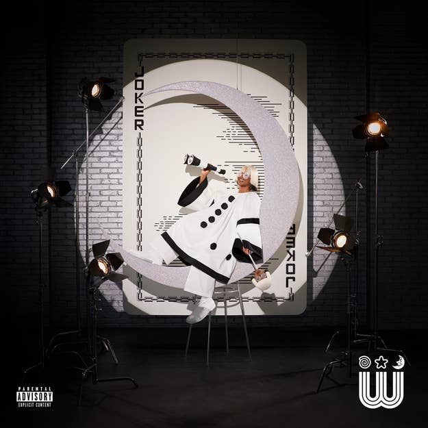 Album cover with artist in a futuristic white outfit posing inside a large letter 'C' surrounded by studio lights