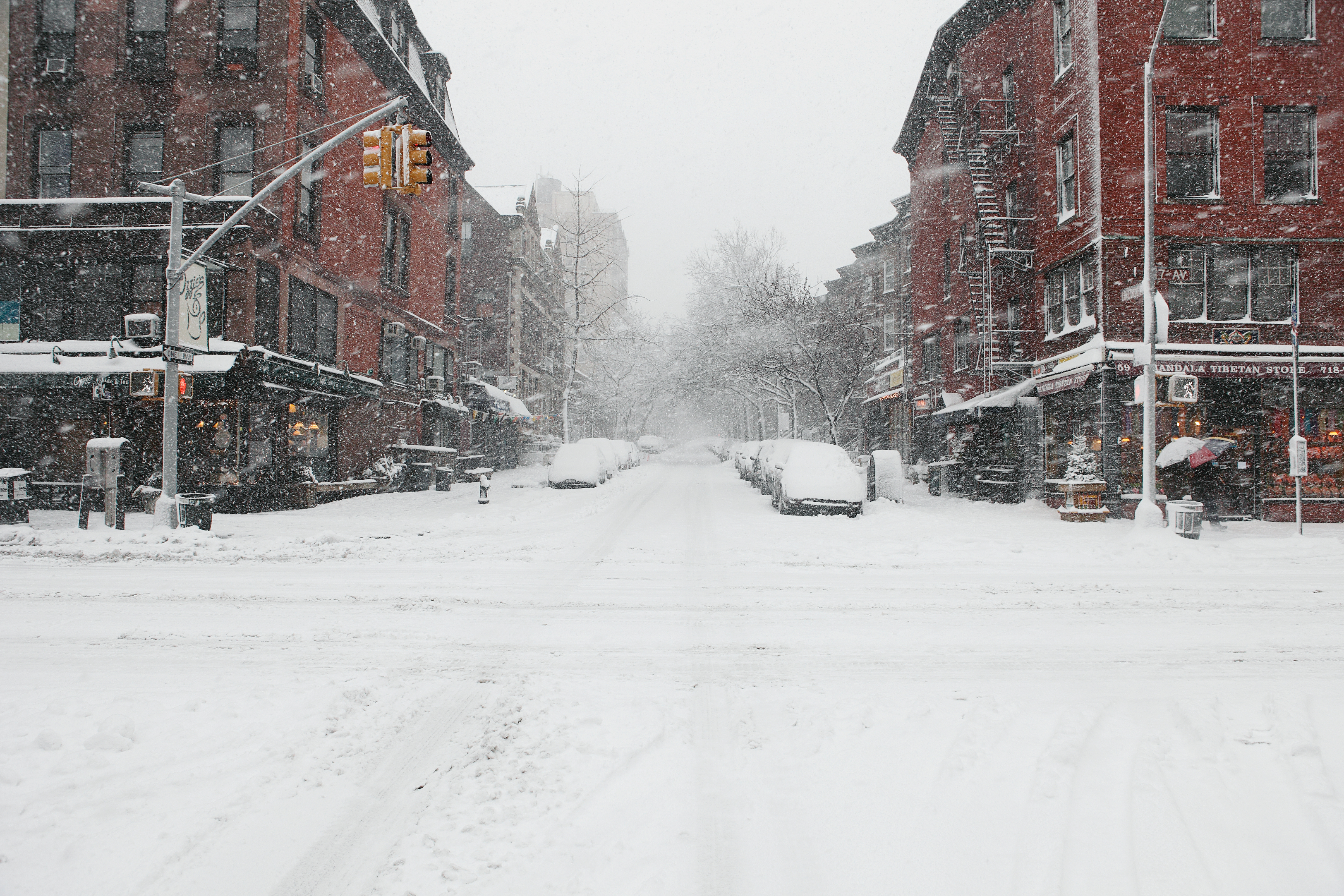Snow-covered street with buildings on both sides, traffic lights, and no visible persons