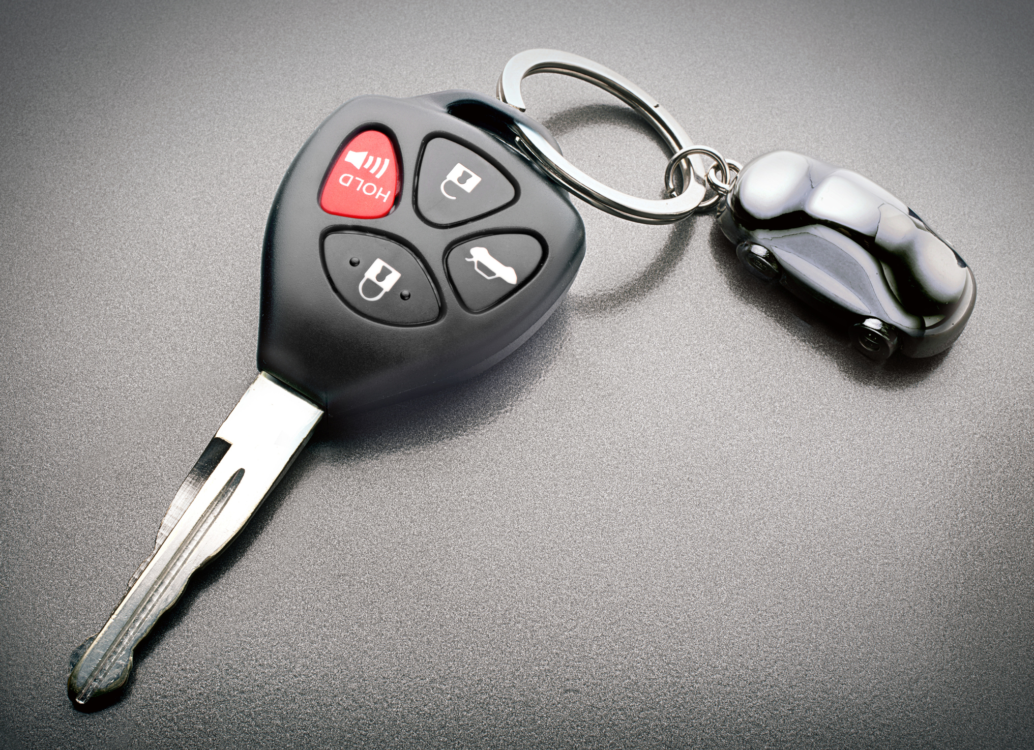 Car key with integrated remote buttons and a keychain shaped like a car