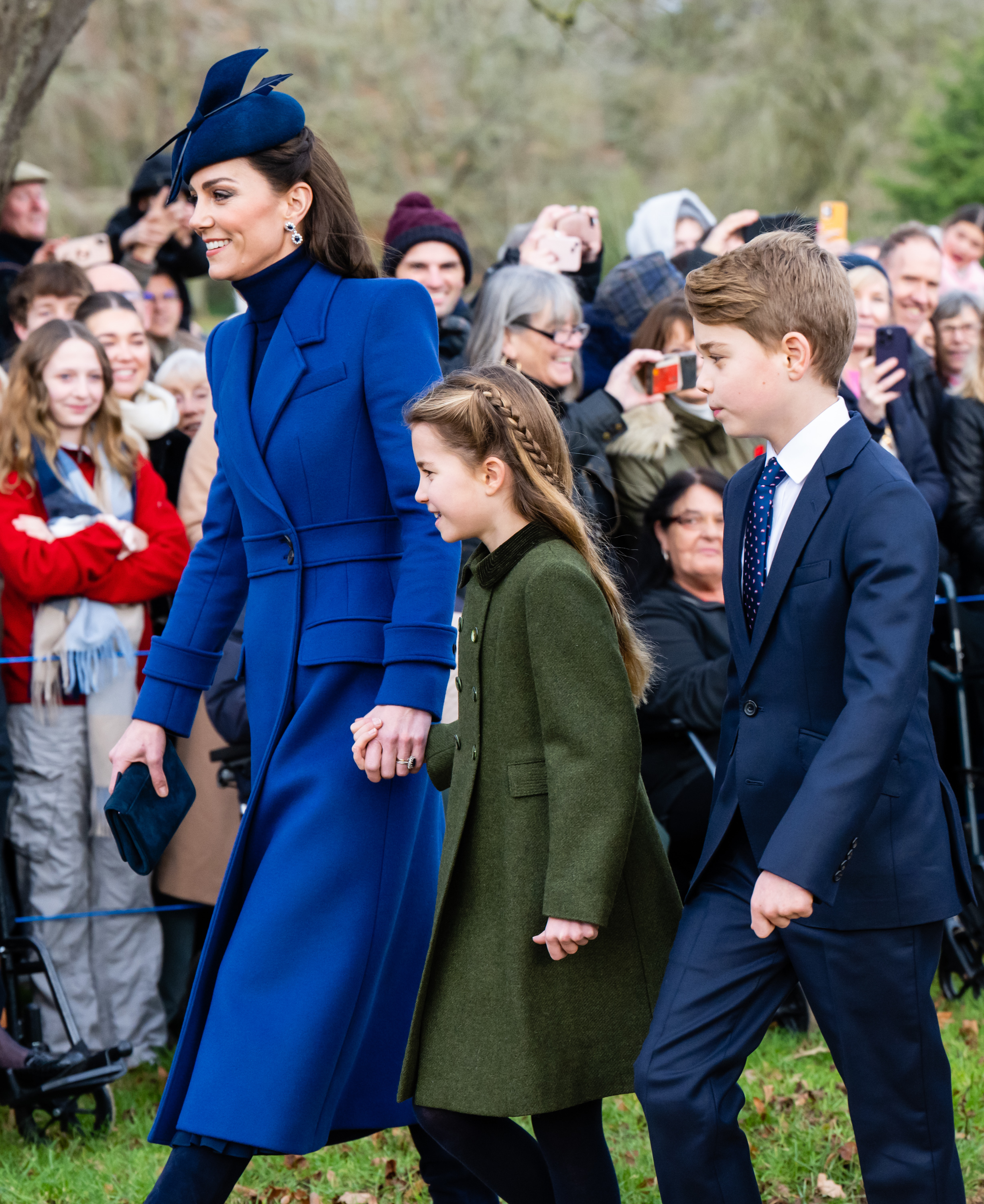 Kate walking with two of her children, George and Charlotte, among a crowd, all dressed in winter coats
