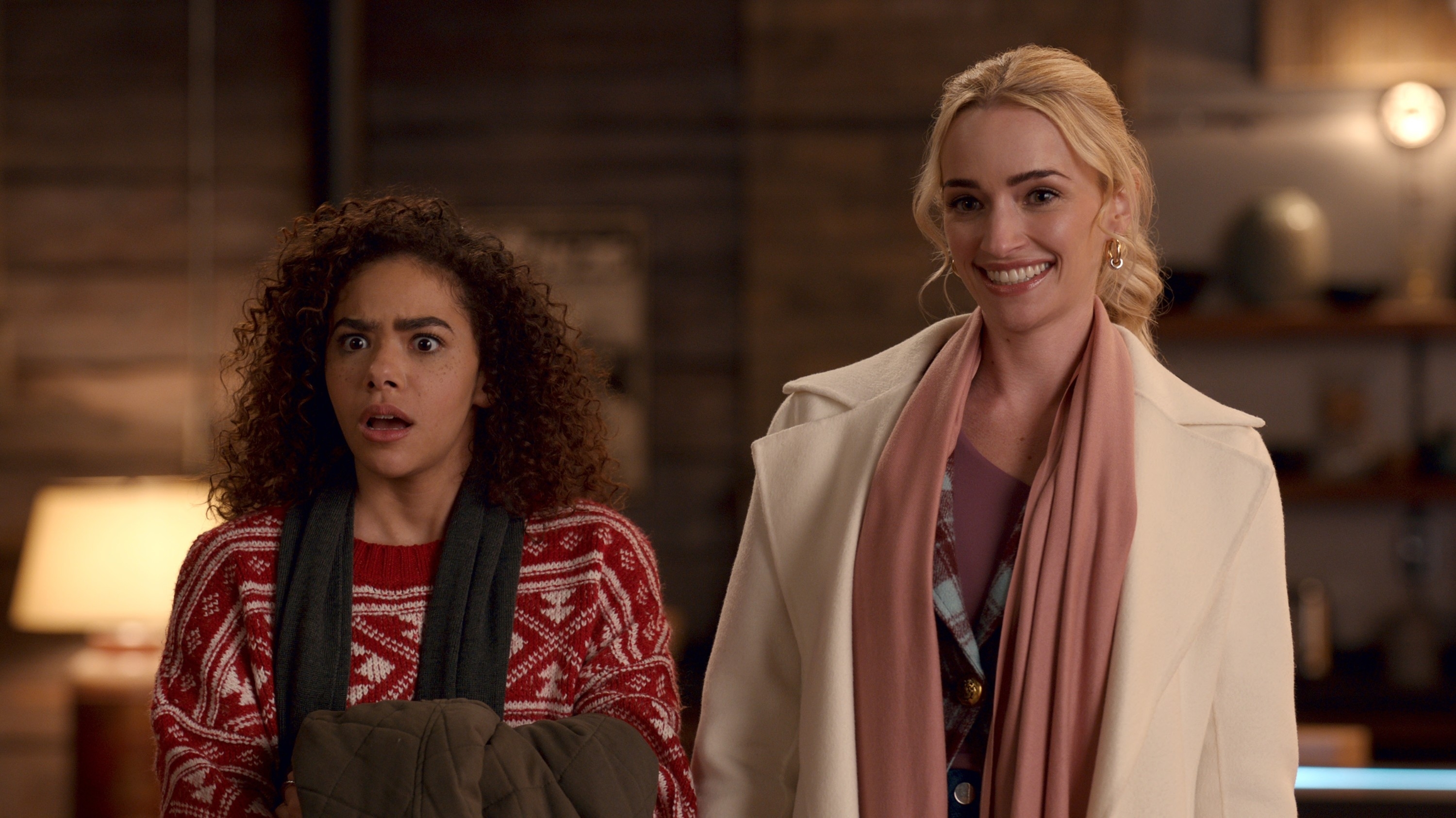 Two women on screen, one wearing a sweater and the other in a coat, expressing surprise