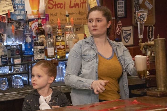 debbie and a younger girl behind the bar, debbie holding a beer