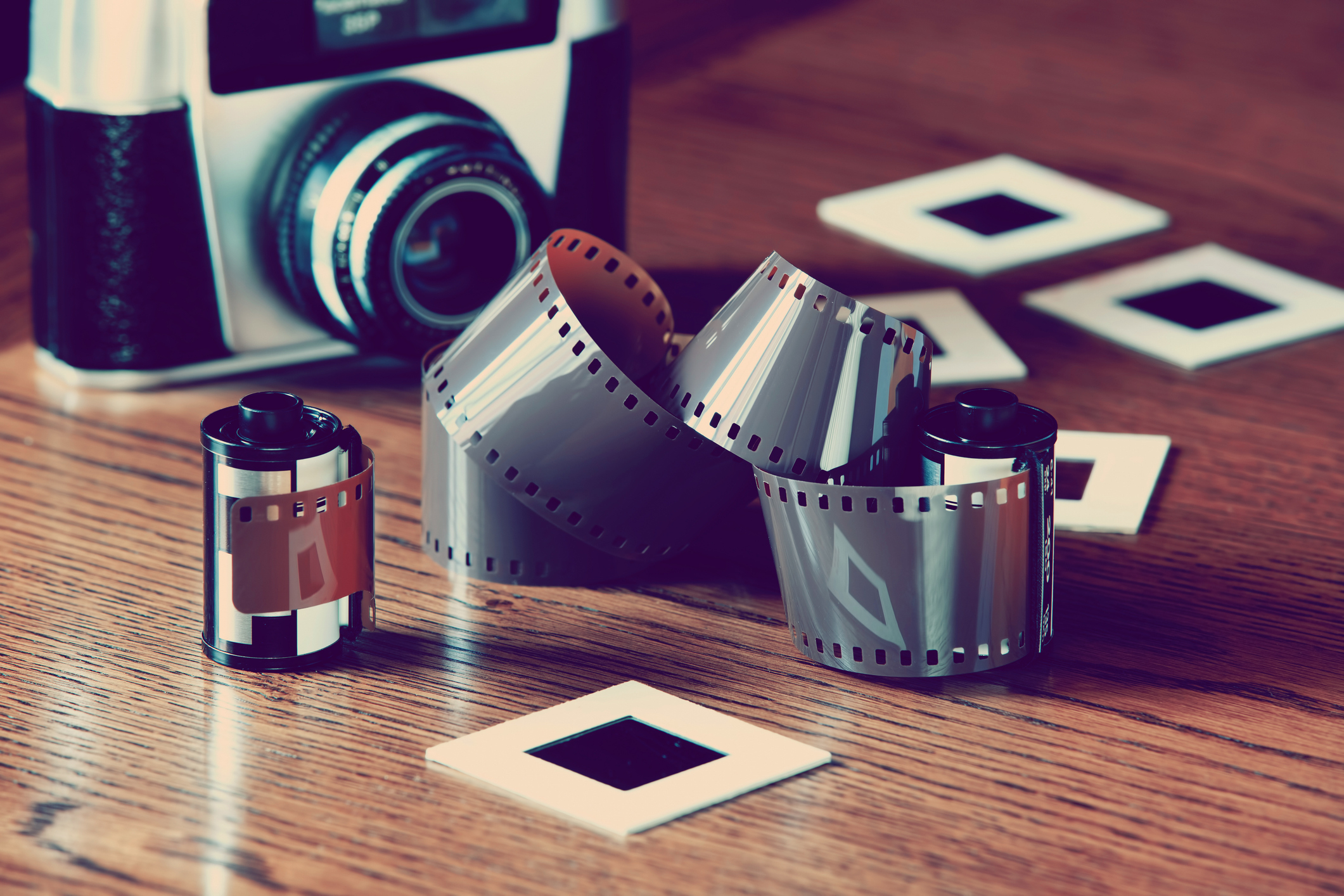 Vintage camera with film rolls and photographs on a wooden surface