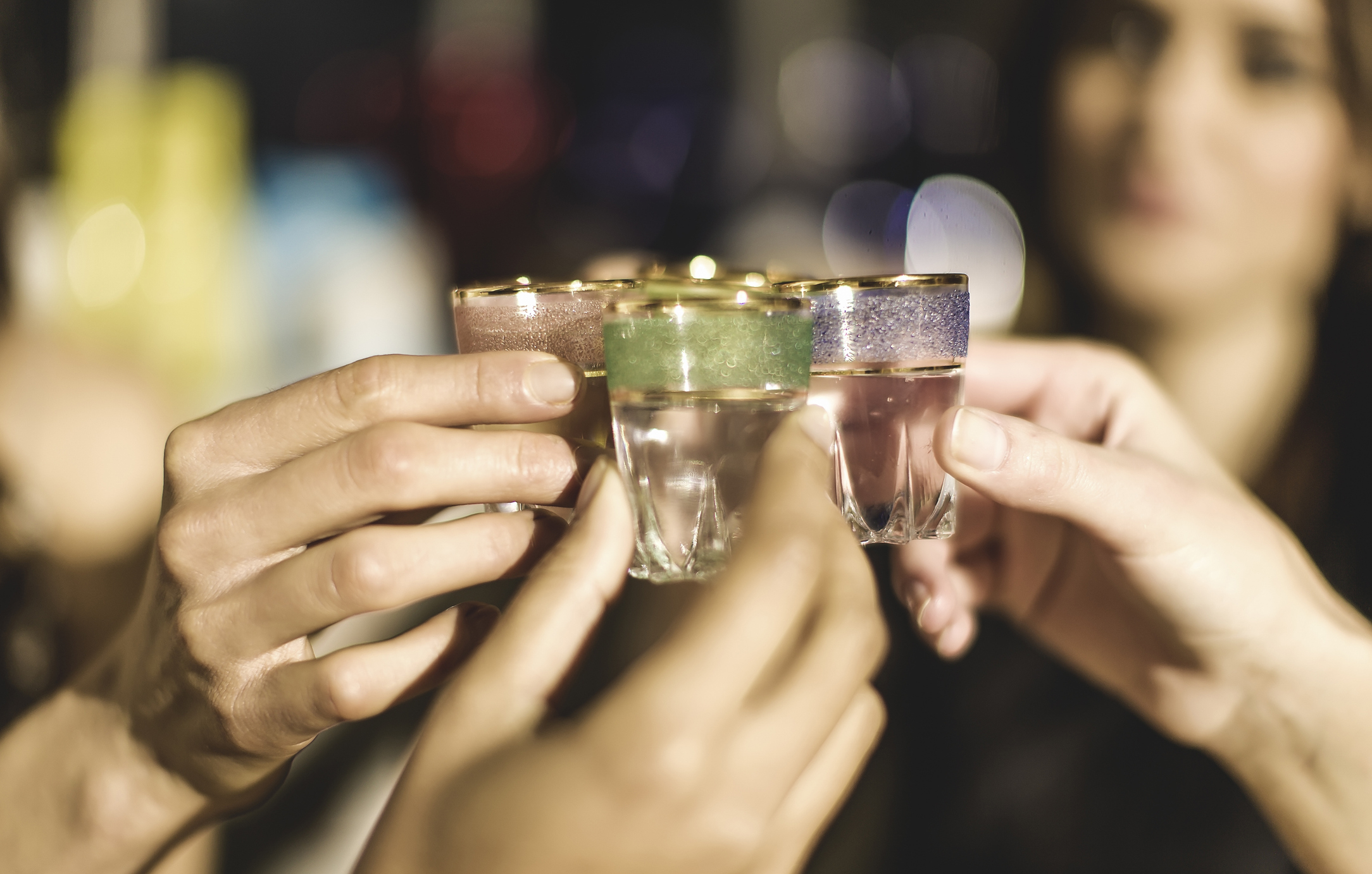 A close-up of people toasting with shot glasses