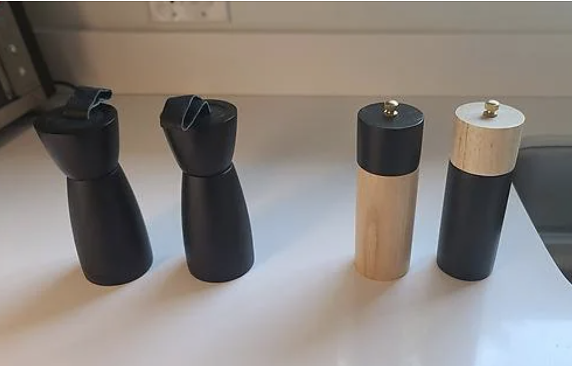 Four modern salt and pepper grinders on a kitchen counter