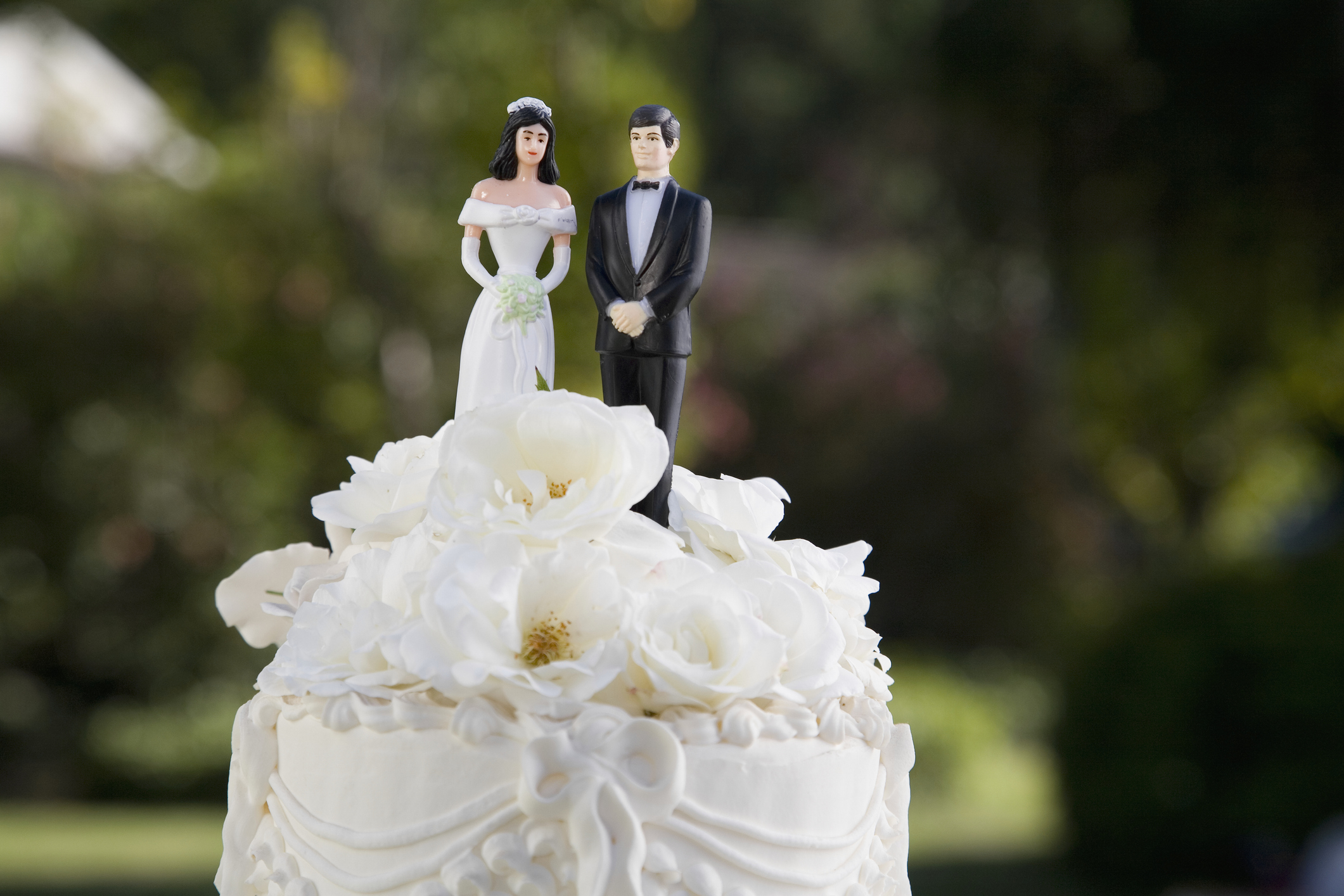 Bride and groom figurines atop a wedding cake with intricate icing details