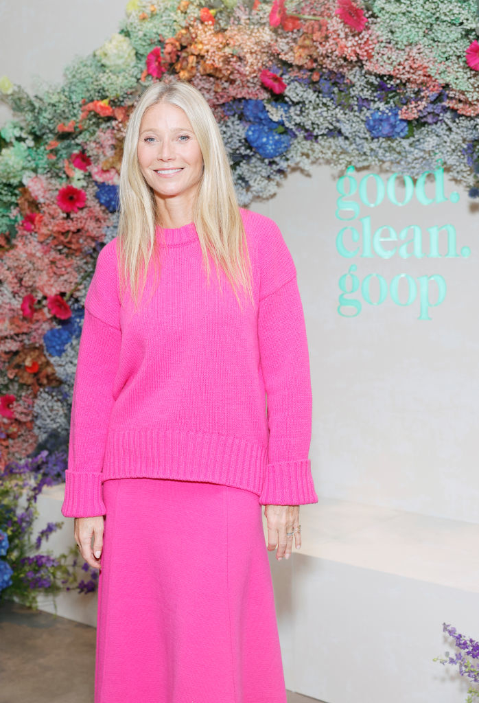 Gwyneth Paltrow in a sweater and skirt at the Goop event with floral background