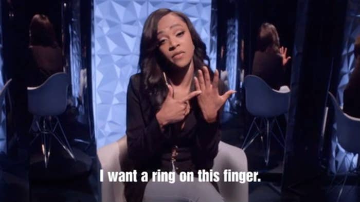 Woman gestures to her ring finger, indicating desire for a ring, with text overlay expressing this wish