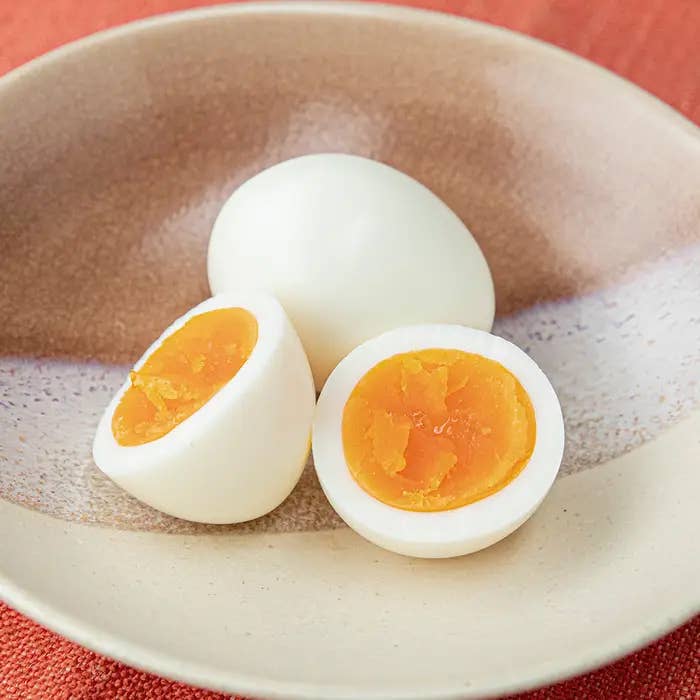 皿の上にある半分にカットされたゆで卵ともう一つの丸いゆで卵です。