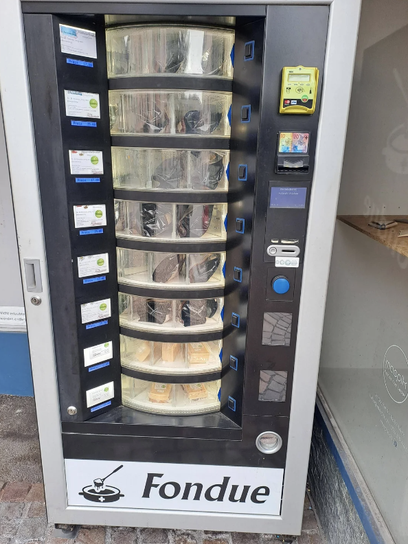 A vending machine with several shelves filled with packaged cheese fondue sets