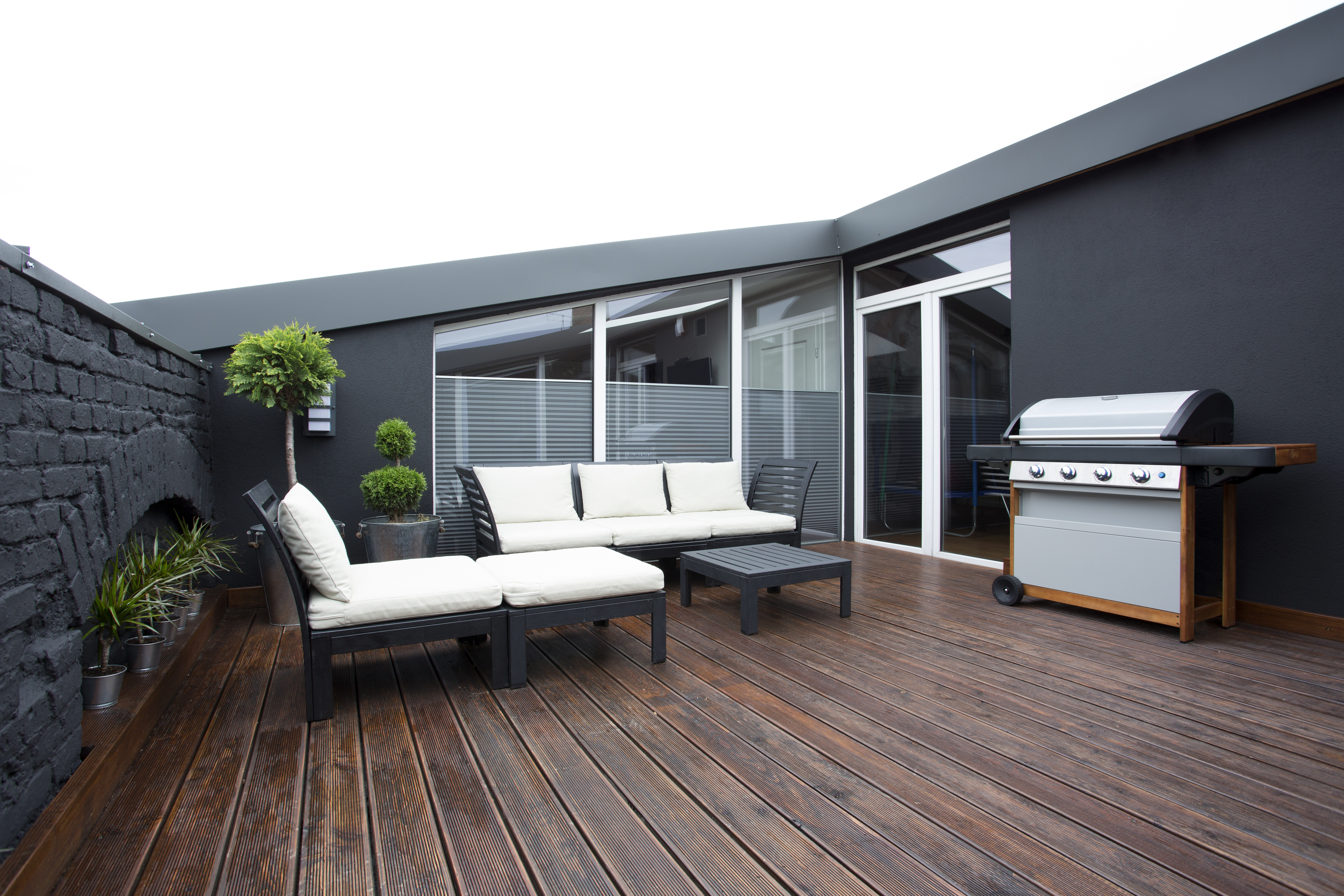 Outdoor patio for a house with a black exterior, with a seating area and a barbecue grill